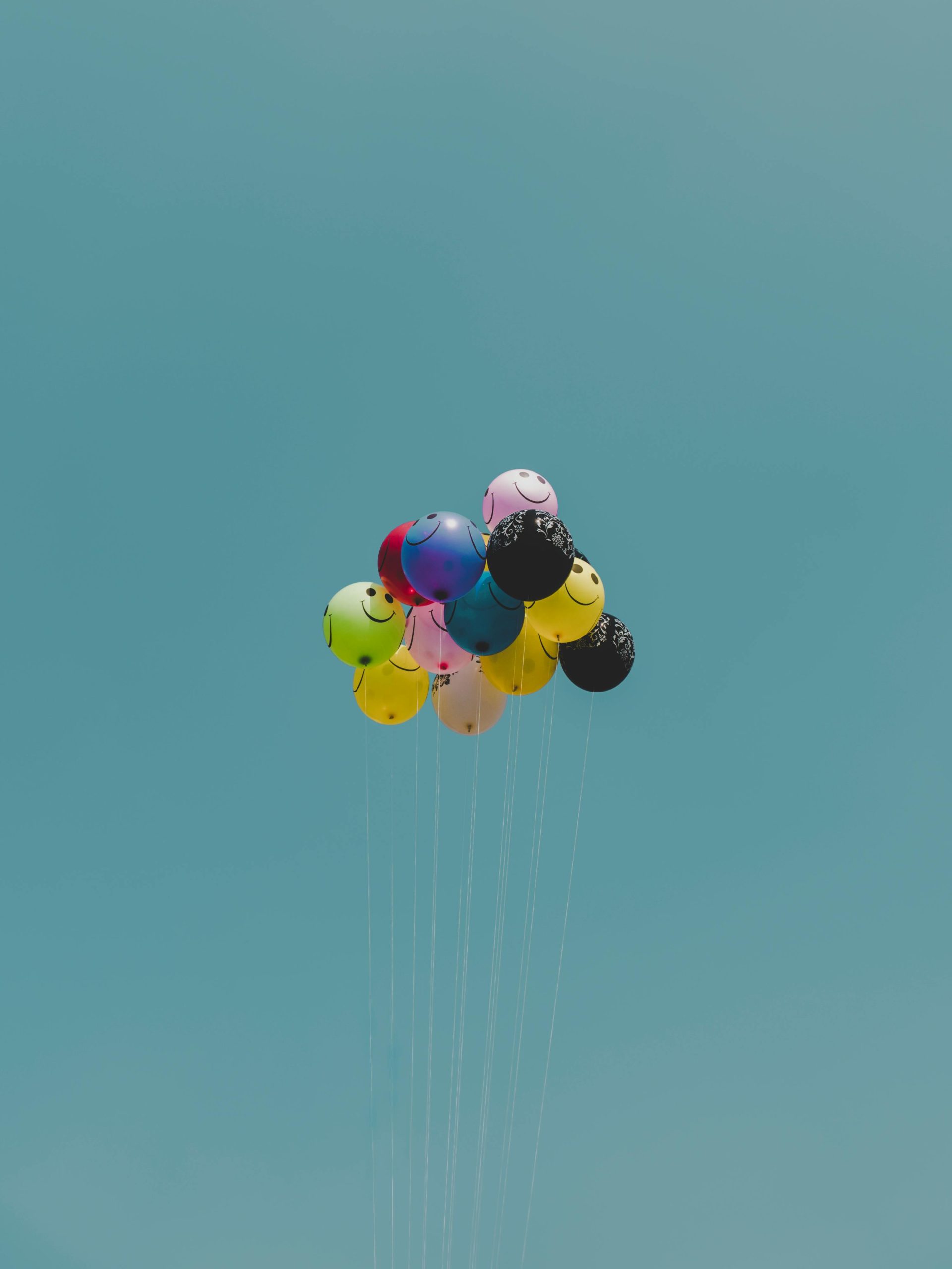 Vibrant helium balloons soar against a bright blue sky, evoking joy and celebration.