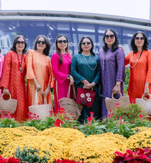 Group of women in vibrant traditional attire smiling outdoors.