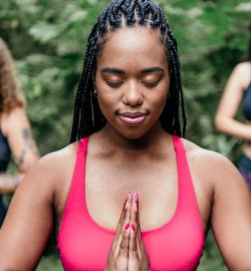 Young woman practicing meditation outdoors, promoting wellness and relaxation.