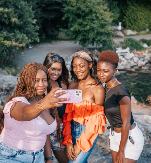A group of four friends taking a cheerful selfie by a scenic lakeside.